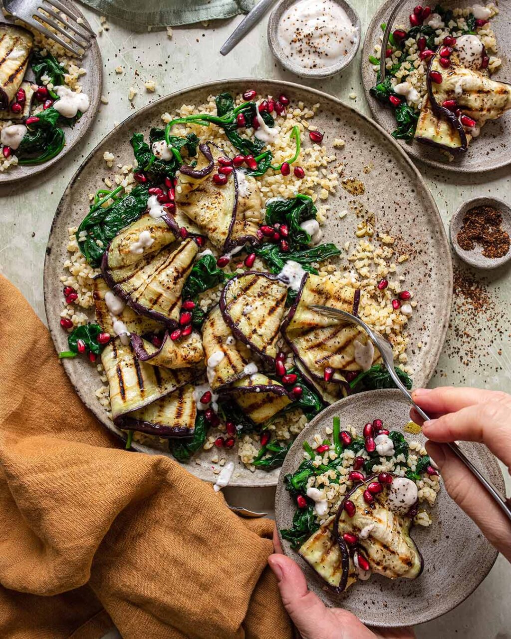 Das Foto zeigt einen Teller mit gegrilltem Auberginensalat, bestreut mit Espresso BBQ Food Finisher, und garniert mit frischen Granatapfelkernen nach Rezept.