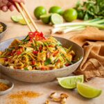 Das Foto zeigt eine Schüssel mit Pad Thai-Salat, angereichert mit "Food Finisher Asia Spice", serviert mit Stäbchen und garniert mit frischer roter Chili nach Rezept.