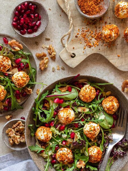 Das Foto zeigt eine Salat Bowl, bestreut mit "Food Finisher Salat & Bowls", mit veganem Feta, Rucola, Granatapfelkernen und Walnüssen.