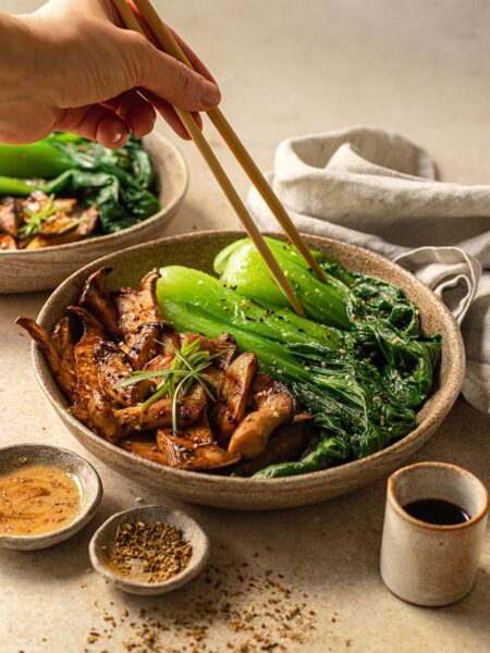 Das Foto zeigt einen rustikalen Teller mit gebratenen Pilzen und grünem Blattgemüse, gewürzt mit "Food Finisher Fisch & Scampi nach Rezept.