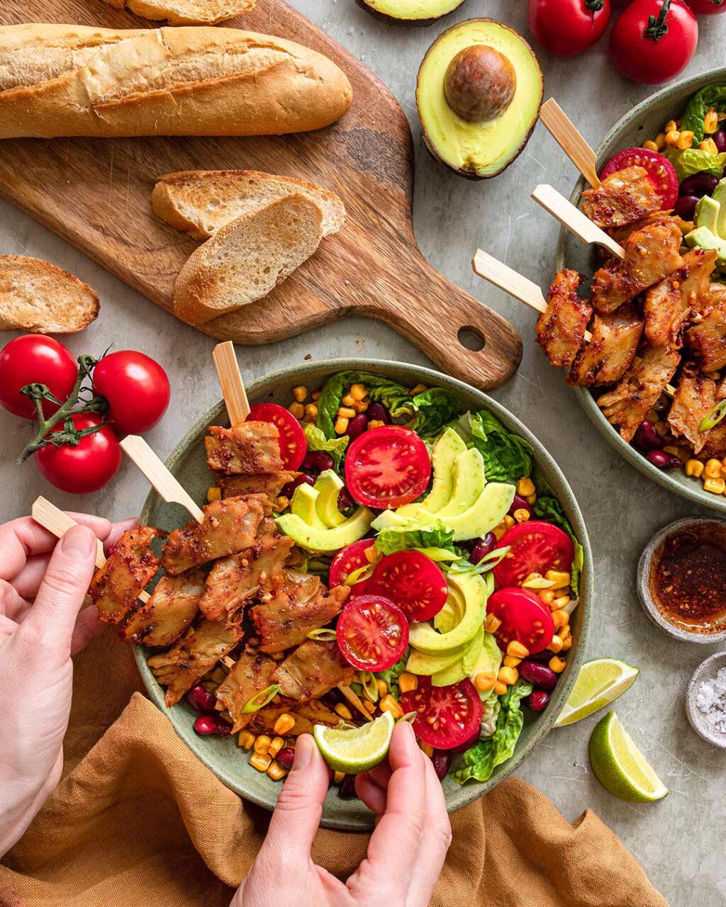 Das Foto zeigt das Gericht Gegrillter Hühnerfleischspieß-Salat nach Finisher-Rezept, serviert mit frischem Baguette und Avocado.