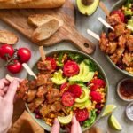 Das Foto zeigt das Gericht Gegrillter Hühnerfleischspieß-Salat nach Finisher-Rezept, serviert mit frischem Baguette und Avocado.