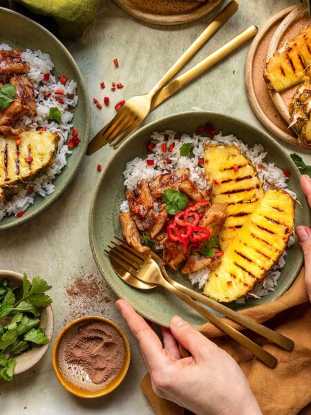 Das Foto zeigt ein gegrilltes (veganes) Hähnchen mit Ananas und Kokosnussreis nach Rezept, garniert mit frischem Koriander und Chilischoten.