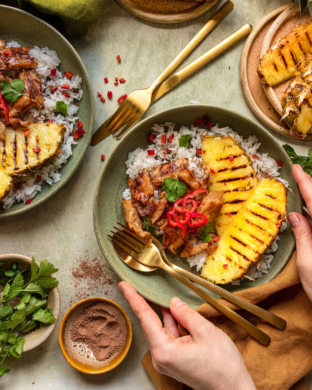 Das Foto zeigt ein gegrilltes (veganes) Hähnchen mit Ananas und Kokosnussreis nach Rezept, garniert mit frischem Koriander und Chilischoten.