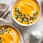 Das Foto zeigt eine cremige Kürbissuppe mit Ingwer und Kurkuma nach Rezept, verfeinert mit Kürbiskernen, BIO ASIA FOOD FINISHER und frischen Kräutern.