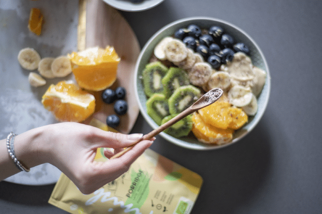 Ein Kühlschrank mit sorgfältig organisierten Lebensmitteln in Glasbehältern und wiederverwendbaren Verpackungen, begleitet von frischen Kräutern und Gemüse. Perfekte Vorbereitung, um die Haltbarkeit der Lebensmittel zu verlängern
