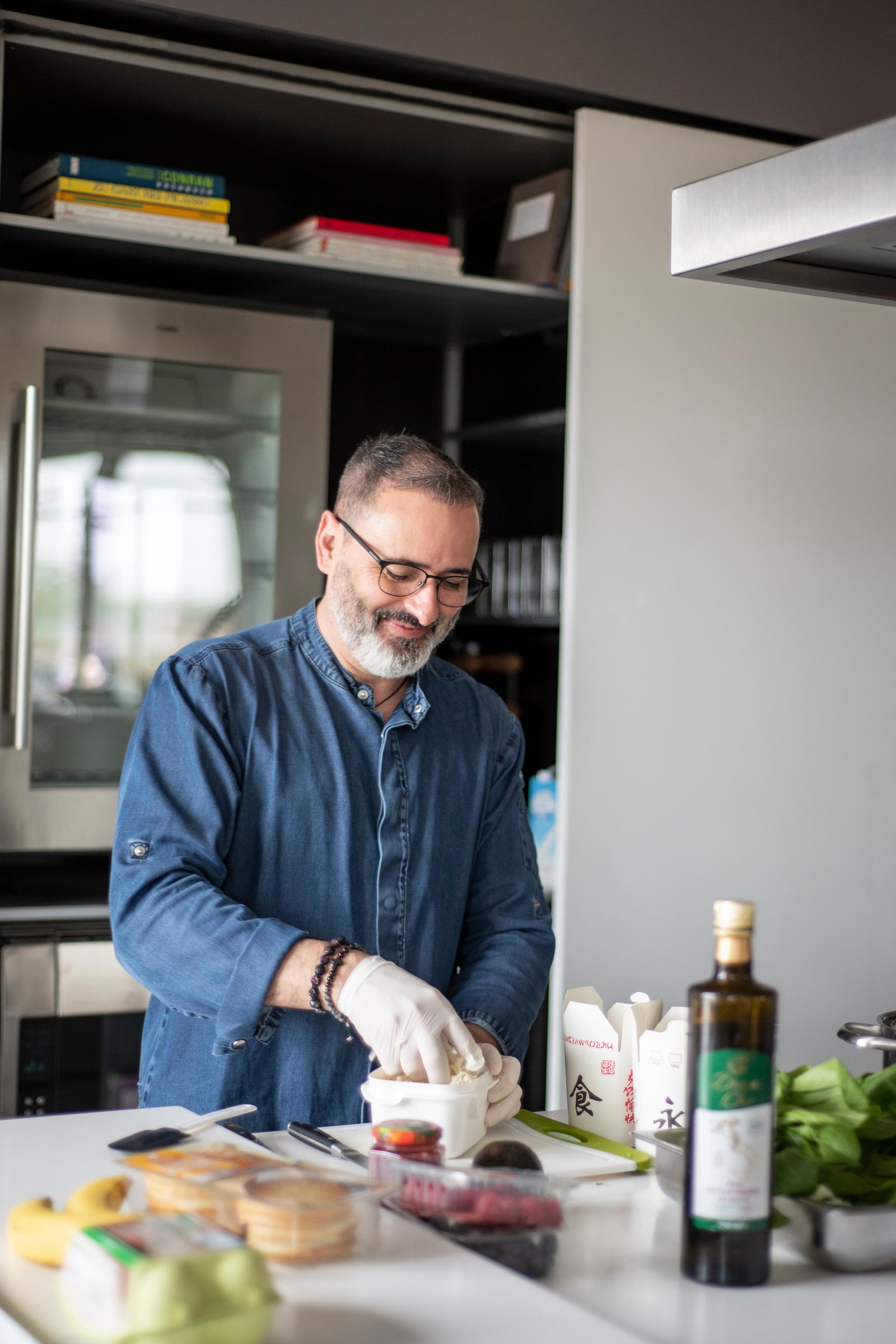 Spitzenkoch Luis Dias aus Köln, in einer Küche, wie er mit Lebensmitteln arbeitet. Auf dem Tisch liegen übriggebliebene Zutaten wie Brot, Gemüse und Kräuter, die er kreativ zu einem neuen Gericht kombiniert. Luis gibt Tipps zur Vermeidung von Lebensmittelverschwendung.