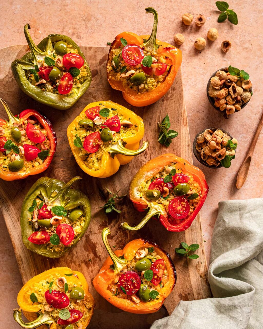 Gefüllte Grillpaprika auf einem Holzbrett, zubereitet nach einem Rezept von Sternekoch Luis Dias aus Köln. Die Paprika sind appetitlich angerichtet und mit einer würzigen Füllung gefüllt, die am oberen Rand der Paprika sichtbar ist. Das Bild zeigt eine Nahaufnahme der Paprika, die eine kräftige, goldbraune Farbe haben.