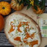 Ein herbstlich angerichteter Kürbis-Flammkuchen, der mit Bio Food Finisher Spices verfeinert wurde, liegt auf einem rustikalen Holzbrett. Die knusprige Kruste und die leuchtenden Kürbisscheiben machen das Gericht besonders appetitlich.