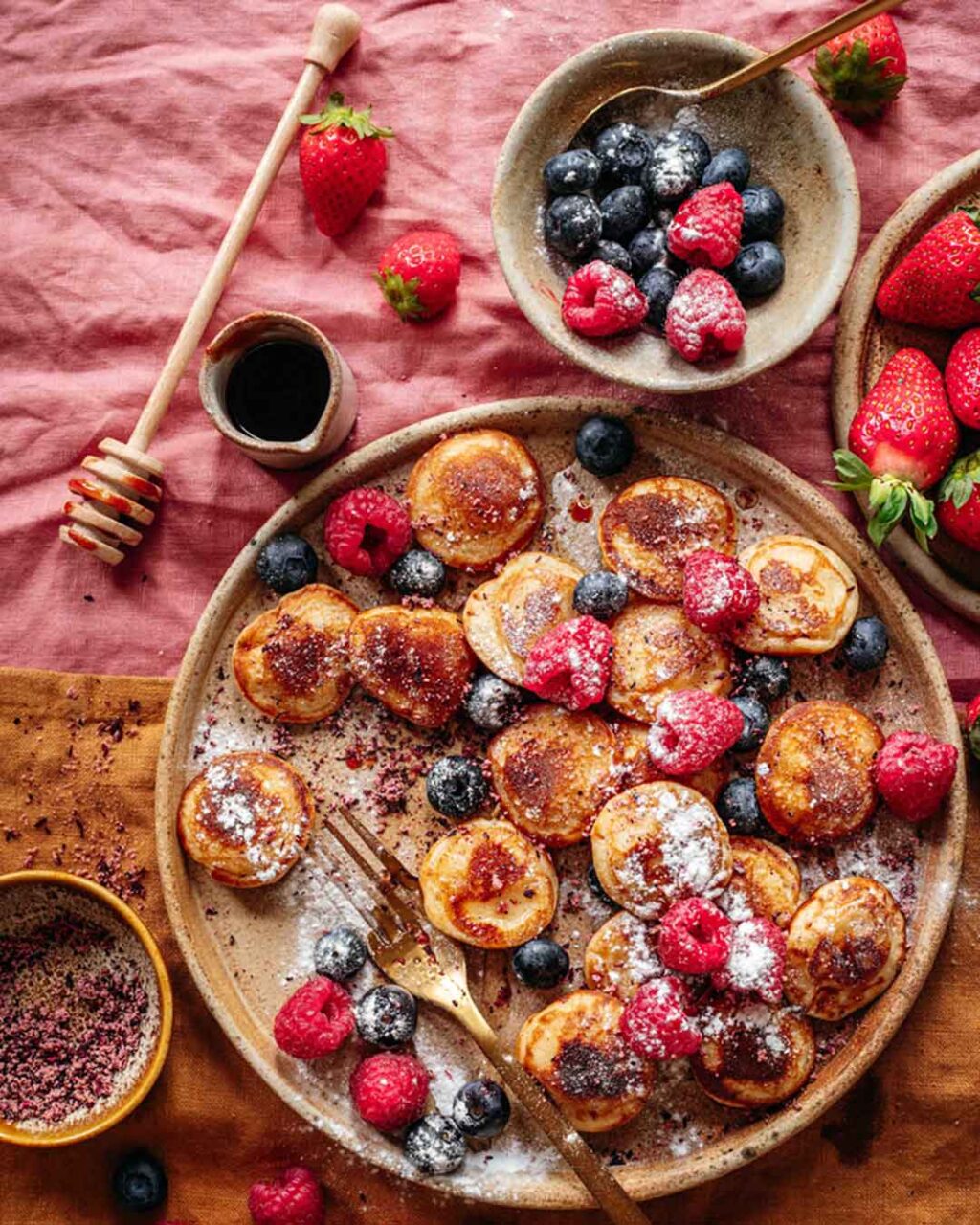 Ein Teller mit frisch gebackenen, Vegane Pancakes verfeinert mit Bio Porridge Food Finisher. Die Pfannkuchen sind locker und fluffig, garniert mit der aromatischen Bio- und veganen Gewürzzubereitung, die aus hochwertigem Hibiskusblüten*, Orangenschalen*, Mangopulver*, getrocknete, gemahlene Datteln*, Tonkabohne* besteht. Ein köstliches Frühstück oder Dessert, das sowohl optisch als auch geschmacklich überzeugt. Das Bild stammt aus einem Rezept von Luis Dias, einem Spitzenkoch.