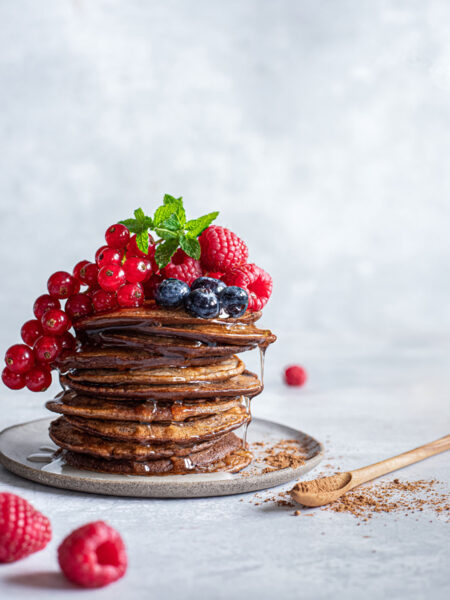 Ein Stapel goldbrauner Pfannkuchen, garniert mit frischen Früchten und einer Prise Kakao Food Finisher – ein süßes und aromatisches Highlight.