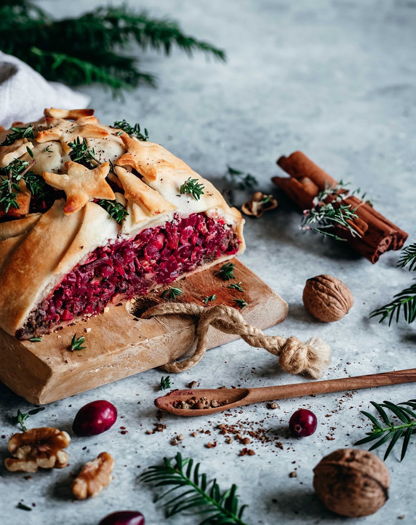 Ein saftiger veganer Nussbraten, goldbraun gebacken und verfeinert mit dem Braten Food Finisher. Das Gericht ist auf einem rustikalen Teller angerichtet, umgeben von Kräutern und einer herzhaften Sauce – ein Festtagsgericht für Genießer.
