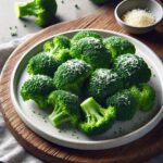 Das Foto zeigt frisch gekochten Brokkoli auf einem Teller, der auf einem rustikalen Holzbrett liegt. Der Brokkoli ist mit geriebenem Parmesan bestreut.