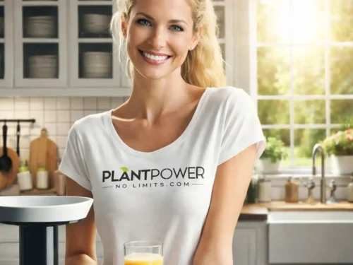Eine lächelnde Frau in einer modernen, hellen Küche, die ein Glas frisch gepressten Saft in der Hand hält. Sie trägt ein weißes T-Shirt mit dem Aufdruck „Plant Power – No Limits.com“, während neben ihr ein Slow Juicer steht, umgeben von frischem Obst und Gemüse.