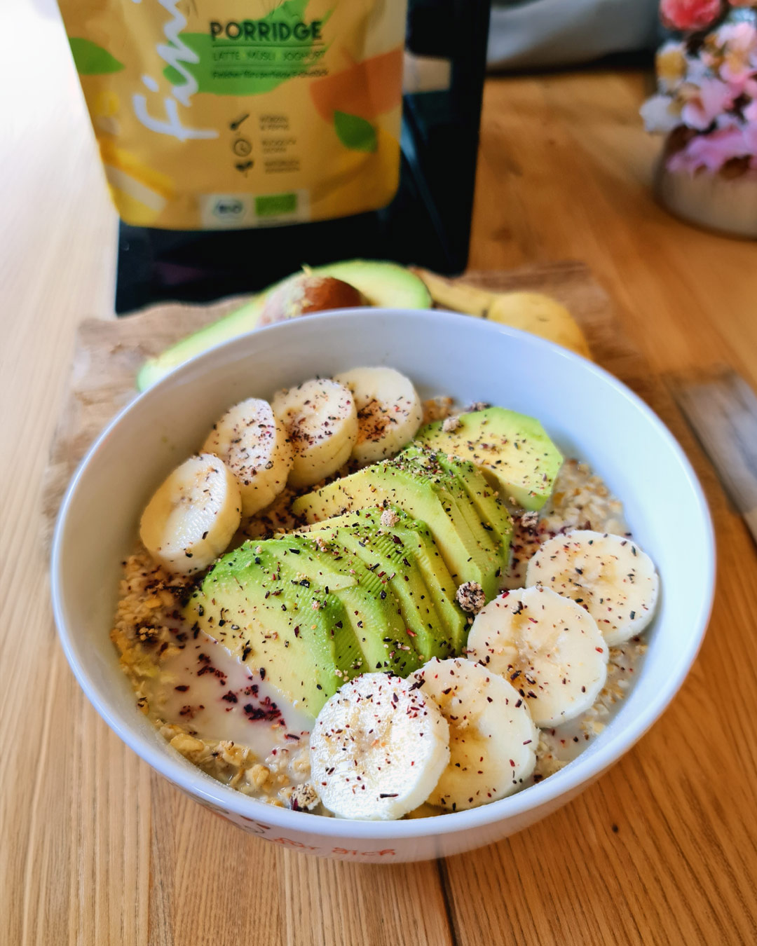 Eine Schüssel mit in Hafermilch eingeweichten Haferflocken, dekoriert mit geschnittener Avocado und Bananenscheiben, verfeinert mit Gewürzen. Ein gesundes Frühstück, das mit dem FoodFinisher Porridge von Luis Dias abgerundet wird.