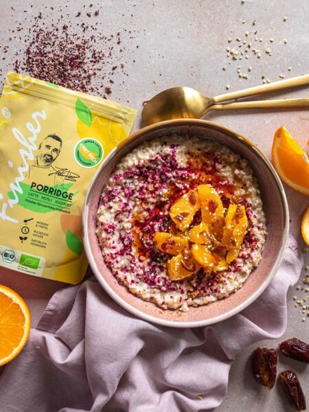 Fruchtiges Orangen-Dattel-Porridge, verfeinert mit dem Bio Porridge Food Finisher. Das Porridge ist mit Orangenstücken, Datteln und einem farbenfrohen Gewürz-Mix dekoriert. Perfektes gesundes Frühstück mit natürlichem Topping.