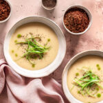 Ein Teller cremige Knoblauch-Pastinakensuppe, garniert mit frischen Kräutern und serviert mit knusprigem Brot – ein gesundes, schnelles Gericht.