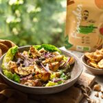 Frischer Salat mit goldbraun gerösteten Kartoffelecken, roten Zwiebeln, Kapern und Gewürzen von Food Finisher Spices vor einer grünen Naturkulisse.