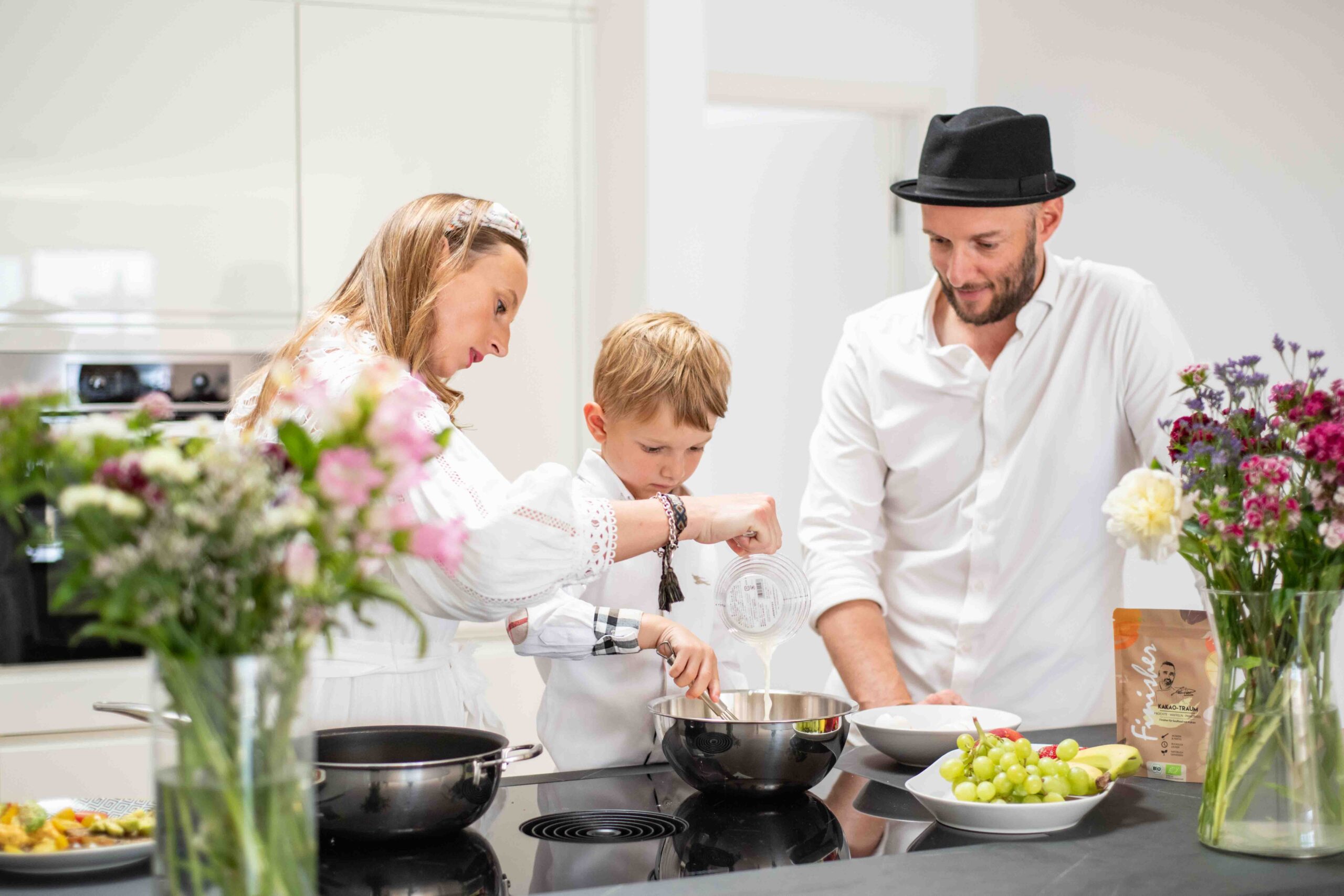 Eine Familie kocht gemeinsam in der Küche, während verschiedene Gewürze auf der Arbeitsfläche stehen. Ein inspirierender Moment für Kochanfänger, um mit Gewürztipps und Tricks den Einstieg in die Küche zu finden.