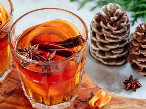 Winterliches Bild mit dampfendem Glühwein im Glas, Tannenzapfen, Zimtstangen und winterlichen Gewürzen. Symbolisiert die aromatische Gewürzvielfalt im Winter mit Food Finisher Spices. Bio-zertifizierte Gewürzmischungen, vegan, ohne Zusatzstoffe.