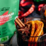Zwei dampfende Glühwein-Gläser, dekoriert mit Zimtstangen und Orangenscheiben. Im Hintergrund sichtbar: Wintergenuss Food Finisher Spices. Aromatische Bio-Gewürzmischung mit Zimt, Hibiskus, Datteln und Tonkabohne. 100 % Bio, vegan, ohne Zusatzstoffe, ideal für die Winterzeit.