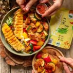 Ein Teller mit süß-saurer Gemüsepfanne, veganem Hähnchen, frischen Zucchini- und Paprikastücken sowie gegrillter Ananas, angerichtet mit dem Bio Chicken Food Finisher von Food Finisher Spices.