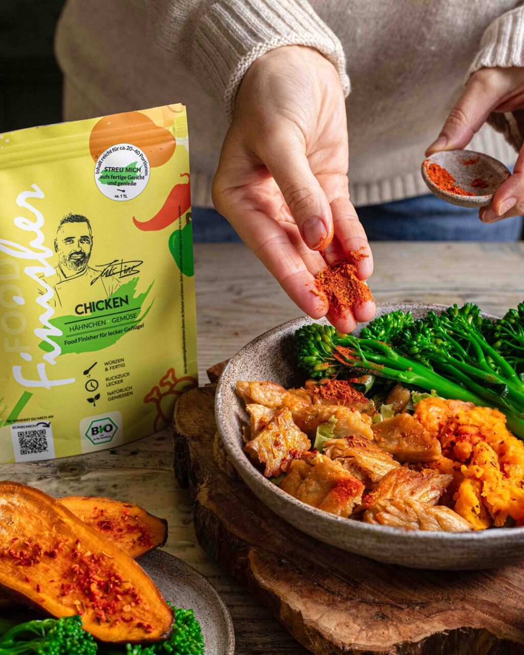 Ein Teller mit saftigem Hähnchen, gerösteten Süßkartoffeln und knackigem Brokkolini, abgerundet mit dem Bio Chicken Food Finisher. Die Zutaten sind appetitlich angerichtet und strahlen Frische und Würze aus.