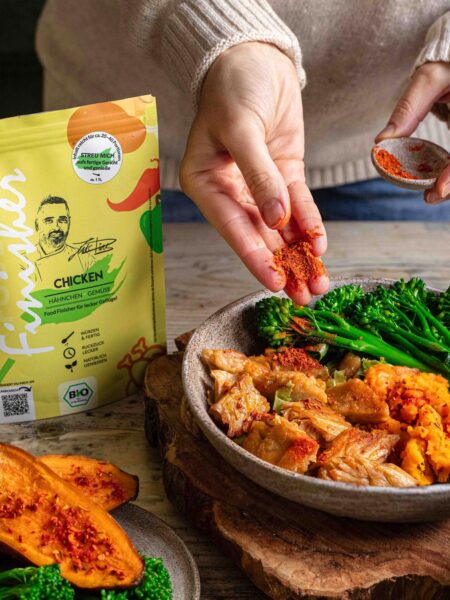 Ein Teller mit saftigem Hähnchen, gerösteten Süßkartoffeln und knackigem Brokkolini, abgerundet mit dem Bio Chicken Food Finisher. Die Zutaten sind appetitlich angerichtet und strahlen Frische und Würze aus.