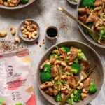 Gewürz Mix Bio Espresso BBQ Food Finisher neben einer Pfanne mit frischem Brokkoli-Cashew-Pfannengemüse. Der Gewürz-Mix verleiht dem Gericht eine einzigartige, würzig-aromatische Note. Perfekt für schnelle und gesunde Mahlzeiten!