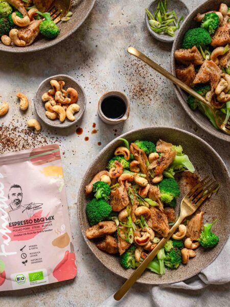 Gewürz Mix Bio Espresso BBQ Food Finisher neben einer Pfanne mit frischem Brokkoli-Cashew-Pfannengemüse. Der Gewürz-Mix verleiht dem Gericht eine einzigartige, würzig-aromatische Note. Perfekt für schnelle und gesunde Mahlzeiten!
