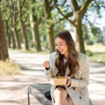 Eine junge Frau sitzt entspannt auf einer Parkbank und genießt einen gesunden, bunten Salat. Die frische Luft und die natürliche Umgebung unterstreichen ihren bewussten Ernährungsstil.