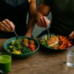 Zwei sportliche Personen in Performance-Shirts essen eine bunte pflanzenbasierte Bowl; daneben eine Bowl mit gegrillter Proteinbeilage.